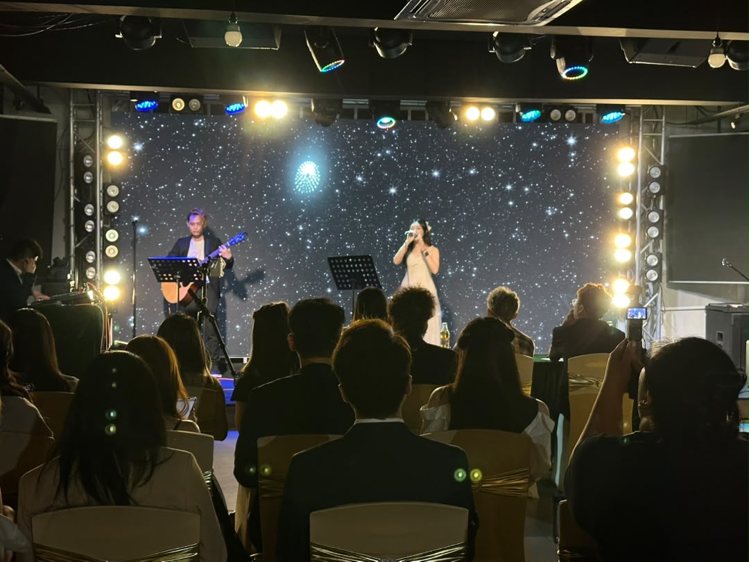 Acoustic duo performing on stage with a starlight backdrop and seated guests at Dreamlive Event Space Puchong